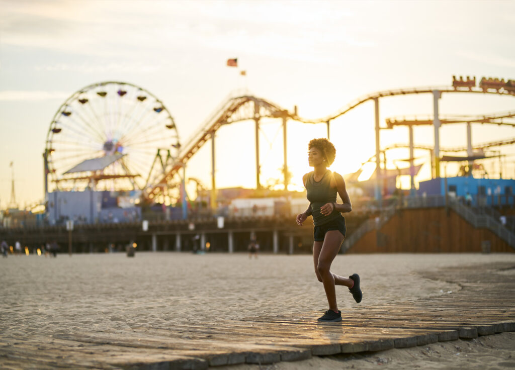 woman jogging on boardwalk at sunset on beach in Los Angeles to celebrate Global Running Day