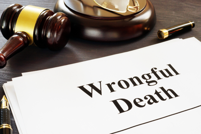 closeup of document that says wrongful death on top of a brown desk, near a gavel